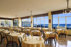 a dining room with tables and chairs and the ocean at Hotel Bristol in Laigueglia