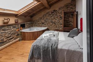Apartamentos Rurales Casa Llongo في Coaña: غرفة نوم مع حوض استحمام وسرير في غرفة