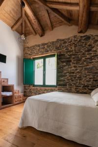Un dormitorio con una pared de ladrillo y una cama en Apartamentos Rurales Casa Llongo en Coaña