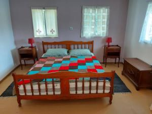 a bedroom with a wooden bed with a colorful quilt at Dada House Nature Holiday in Gornja Čemernica +16 photos