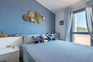 niebieska sypialnia z łóżkiem i oknem w obiekcie Seafront Villa with private pool w mieście Marongiu +32 zdjęcia