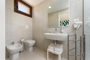a white bathroom with a sink and a toilet at Residence Le Piscine in San Vito lo Capo +14 photos