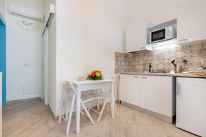 a white kitchen with a table and a counter top at Palazzo Borgomonte - holiday home in Otranto +18 photos