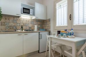 a white kitchen with a table and a microwave at Palazzo Borgomonte - holiday home in Otranto