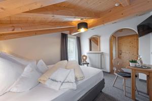 a bedroom with a large white bed with a wooden ceiling at Hotel Torgglerhof in Bressanone