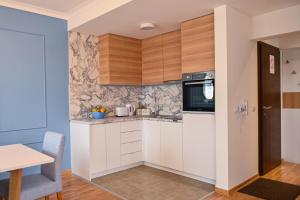 a kitchen with white cabinets and a table at NIDEHO Estate Apartmani in Zlatibor