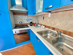 een keuken met blauwe kasten en een roestvrijstalen wastafel bij Residenza le quattro palme in Alghero