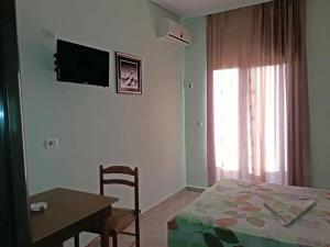 1 dormitorio con cama, mesa y TV en la pared en Tani's Guesthouse, en Ksamil
