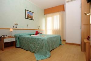 a hotel room with a bed with a green blanket at Hotel Prater in Grottammare +21 photos