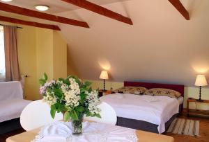 1 dormitorio con 2 camas y un jarrón de flores sobre una mesa en Penzion Kremenisko, en Banská Štiavnica
