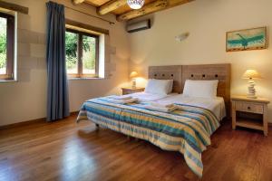 a bedroom with a large bed and two windows at Villa Erontas - private heated jacuzzi in Makhairoí