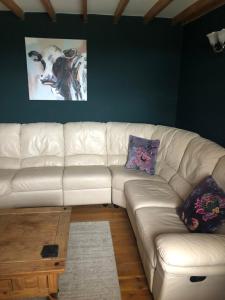 um sofá branco numa sala com uma imagem de uma vaca em Bogma Cottages em Durham