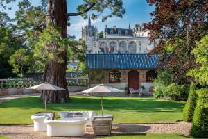 a garden with chairs and umbrellas in front of a castle at Le Clos Richelieu in Amboise