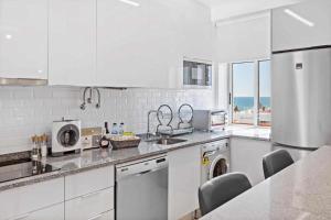 a white kitchen with a sink and a dishwasher at Timeless Sea I Apartment in Armação de Pêra
