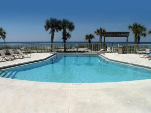 a large swimming pool with palm trees and the ocean at Boardwalk Beach Hotel in Panama City Beach
