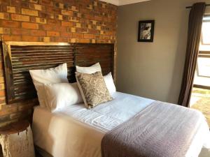 Ce lit se trouve dans une chambre dotée d'un mur en briques. dans l'établissement Rondebosch Eco Cottages, à Middelburg