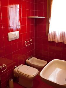 ラ・マッダレーナにあるHotel Garibaldiの赤いタイル張りのバスルーム(トイレ、シンク付)