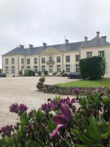 a large white house with purple flowers in front of it at Le Château de Quinéville in Quinéville +18 photos