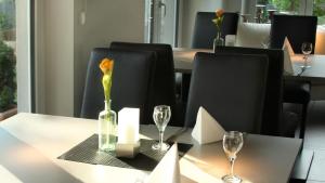 una mesa con un jarrón con una flor y vasos. en Hotel Zur Post en Tréveris