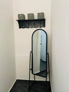 einen Spiegel an einer Wand mit einem Stuhl und einem Regal in der Unterkunft Comfortbnb -Sabbia Calda 8 in Perissa
