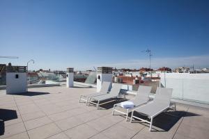 Azahar de Sevilla Apartments في إشبيلية: مجموعة من الكراسي البيضاء على السطح