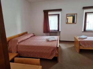 a hotel room with two beds and two windows at Albergo Spina in Pontebba