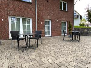 eine Terrasse mit Tischen und Stühlen vor einem Backsteingebäude in der Unterkunft Gaestehaus Savo in Nürburg