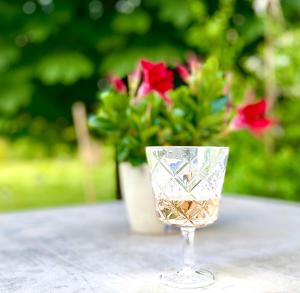 a wine glass sitting on a table with a vase of flowers at Die Zeitwohnung in Hochheim am Main