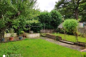 a garden with a lawn with trees and a fence at Cozy Entire Bungalow House in Winchmore Hill