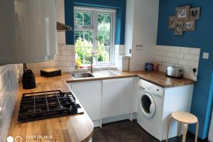 a kitchen with a sink and a washing machine at Cozy Entire Bungalow House in Winchmore Hill