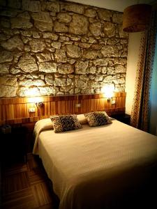 a bedroom with a large bed with a stone wall at Papiroom's in Siracusa
