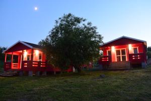 twee rode huisjes in een veld met een boom bij Zatoka Zabłockich in Żnin