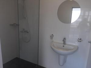a white bathroom with a sink and a shower at Hotel Mistral in Nesebar