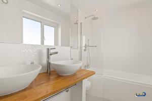 a white bathroom with two sinks and a tub at Am Byth - Luxury Cottage, Sea Views in Saundersfoot