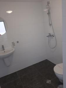 a bathroom with a shower and a toilet and a sink at Hotel Mistral in Nesebar