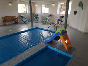 Zimmer mit einem Pool mit Rutsche und Stühlen in der Unterkunft Hennebjerg overnatning in Stavsø