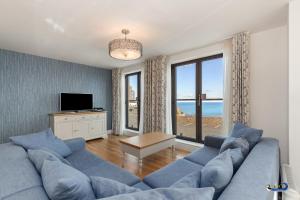 a living room with a blue couch and large windows at Apartment 8 Waterstone House - Luxury Apartment, Sea Views, Pet Friendly in Tenby
