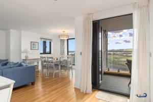 a living room with a blue couch and a dining room at Apartment 8 Waterstone House - Luxury Apartment, Sea Views, Pet Friendly in Tenby