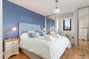 a bedroom with a large white bed with blue walls at Apartment 8 Waterstone House - Luxury Apartment, Sea Views, Pet Friendly in Tenby