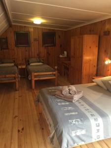 a bedroom with two beds in a room with wooden walls at Bay Cove Inn in Jeffreys Bay