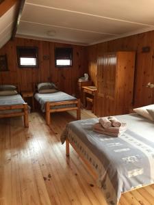 1 dormitorio con 2 camas, suelo de madera y ventanas en Bay Cove Inn, en Jeffreys Bay