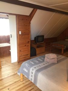 een slaapkamer met een bed en een televisie bij Bay Cove Inn in Jeffreys Bay