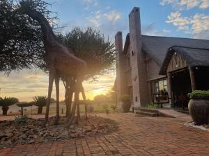 a statue of a giraffe standing next to a building at Sundowners Game Lodge in Marble Hall