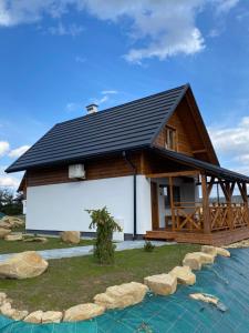 a house with a black roof and some rocks at Holickie Berdo in Polańczyk