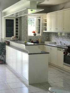 a kitchen with white cabinets and a counter top at Villa Amalaya in Flampouria +27 photos
