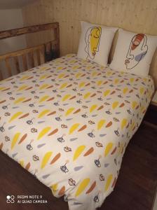 a bed with a white comforter with drawings on it at la ferme de fenivou in Boulieu-lès-Annonay