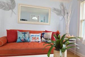 a red couch with pillows in a living room at Lake Worth Beach Paradise Cove Cottage 2-1Bedroom in Lake Worth