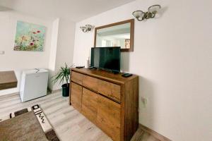 a living room with a tv on a dresser with a mirror at Zur Krone - Ferienhaus 1 in Widdershausen