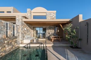 a house with a swimming pool and a stone wall at Acro Suites - A Wellbeing Resort in Agia Pelagia