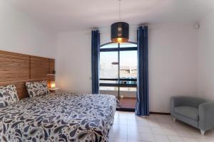 a bedroom with a bed and a chair and a window at Vila Mourisca in Armação de Pêra +21 photos